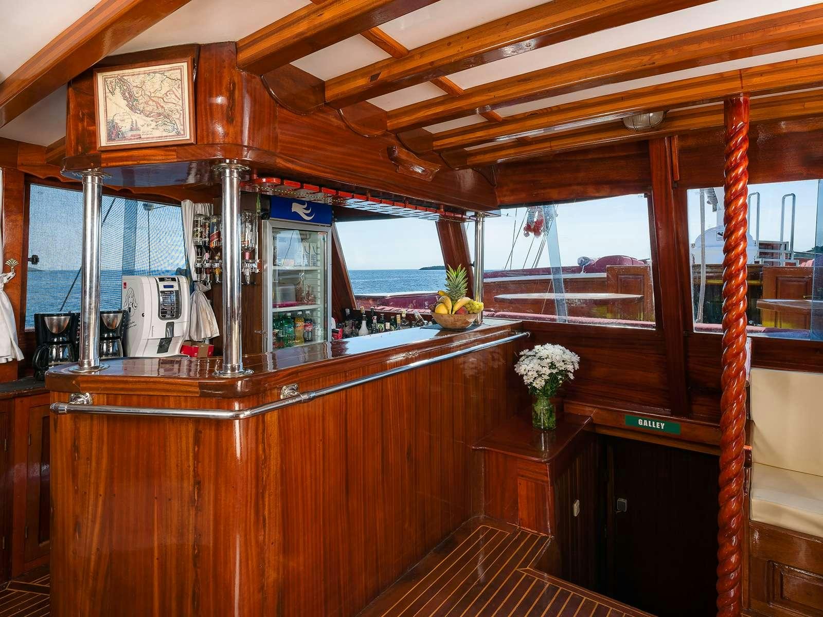 a room with a wood ceiling and a wood table with a vase of flowers on it aboard GULET CROATIA Yacht for Charter