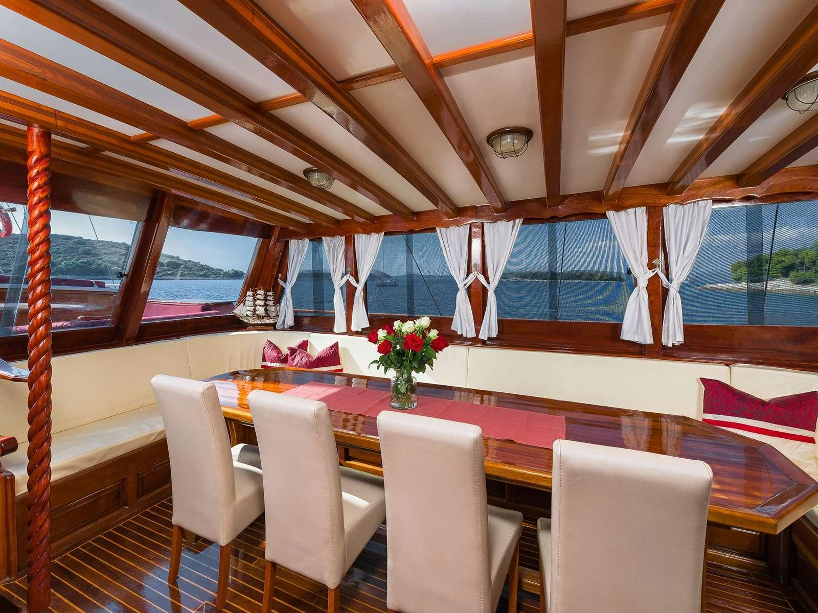a dining table with chairs and a flower vase on it aboard GULET CROATIA Yacht for Charter