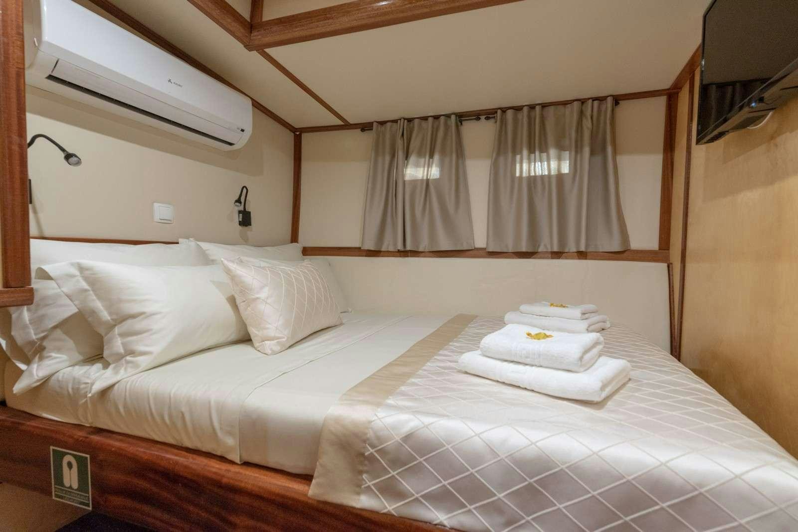 a bed with white sheets aboard Trebenna Yacht for Charter