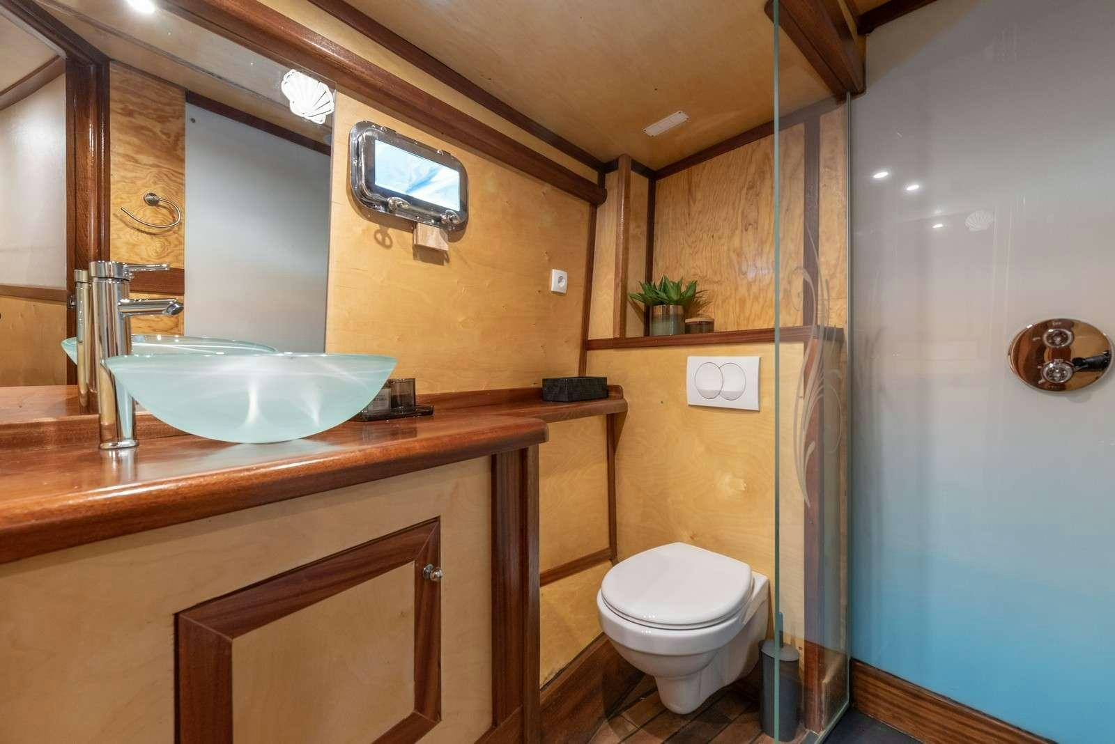 a bathroom with a sink toilet and a mirror aboard Trebenna Yacht for Charter
