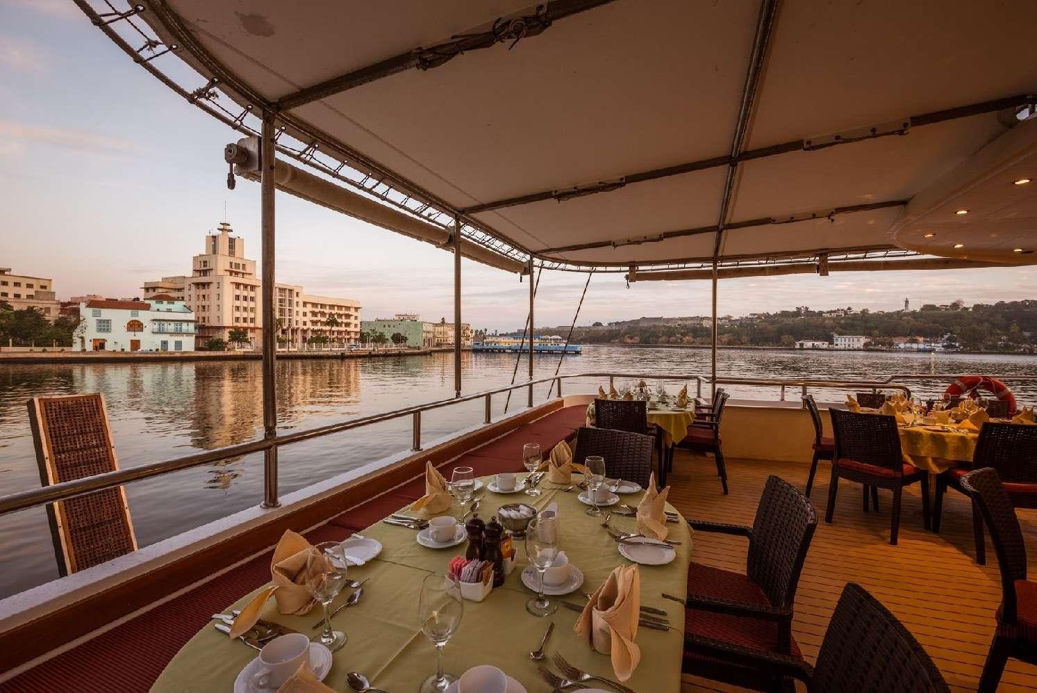 a table set for a meal on a balcony overlooking a city aboard PAN ORAMA II Yacht for Charter