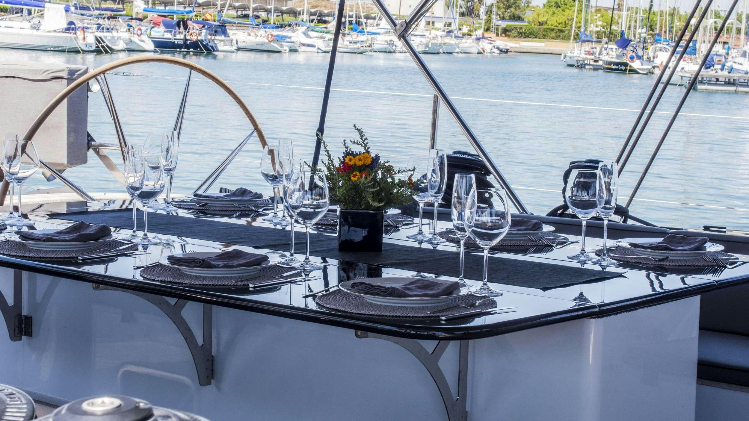 a boat with a flower vase and glasses on it aboard AIZU Yacht for Charter