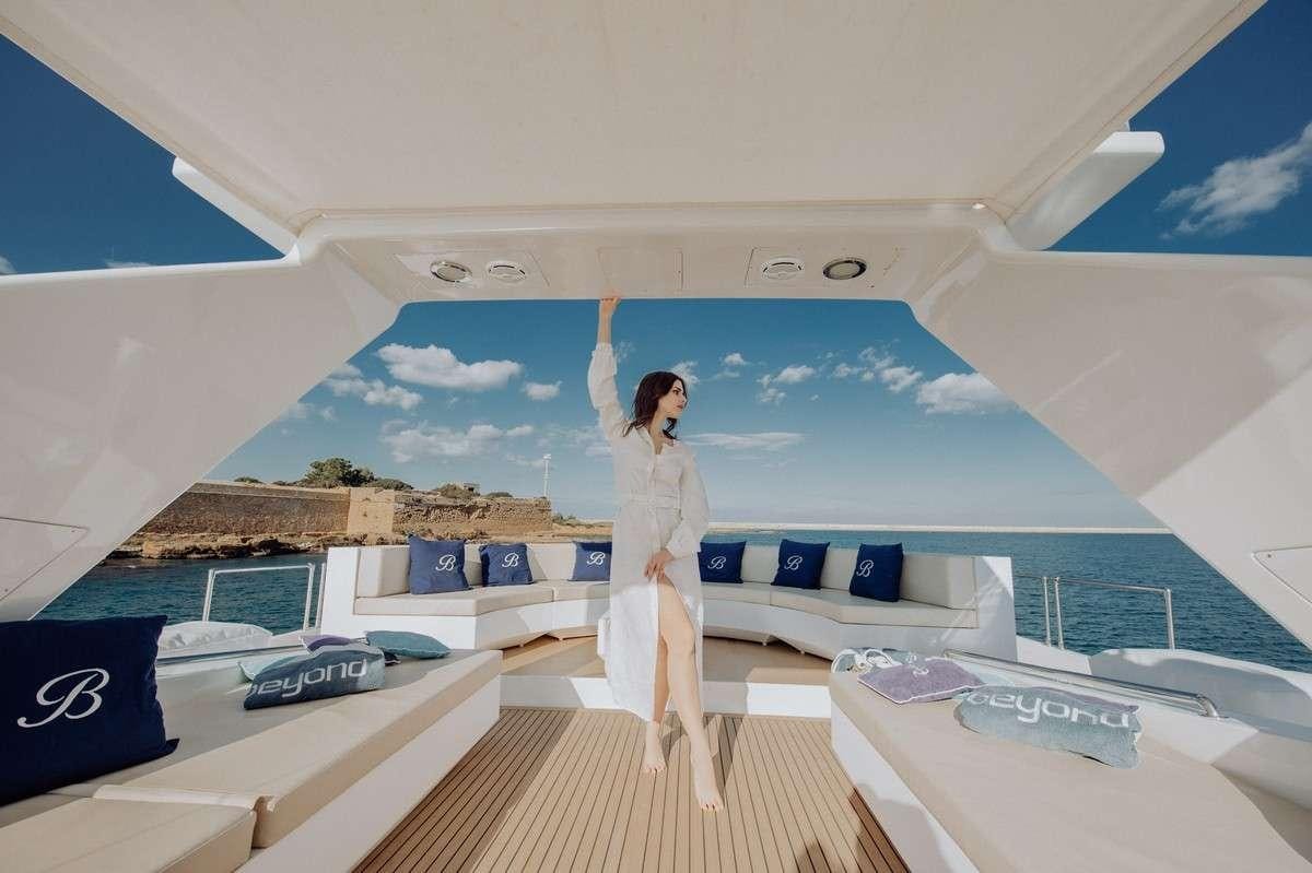 a person in a white dress standing on a balcony aboard BEYOND Yacht for Charter