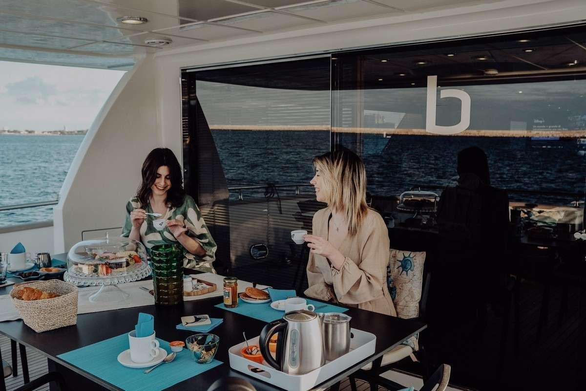 a couple of women sitting at a table with food and drinks aboard BEYOND Yacht for Charter