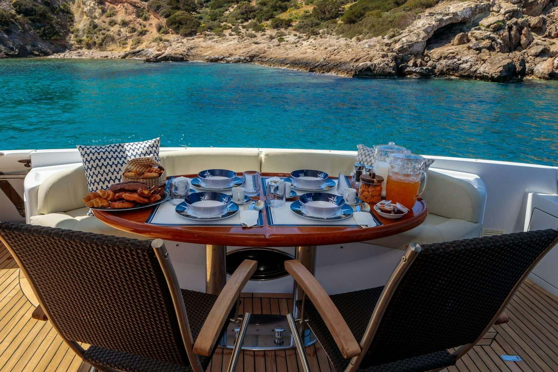 a table with plates and drinks on it by a body of water aboard DREAM Yacht for Charter