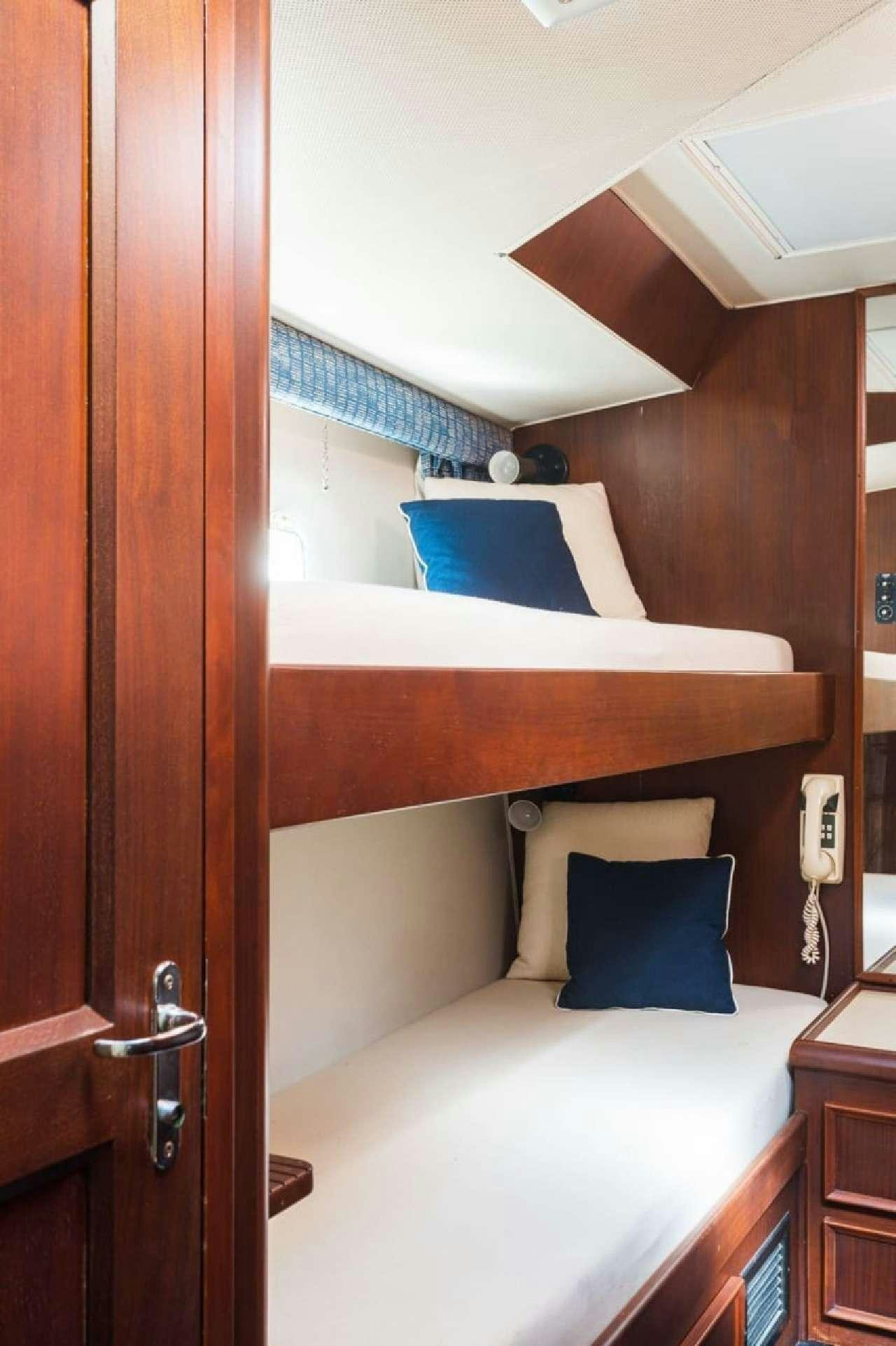 a bed with a white bed and blue pillows aboard Theoxenia Yacht for Charter