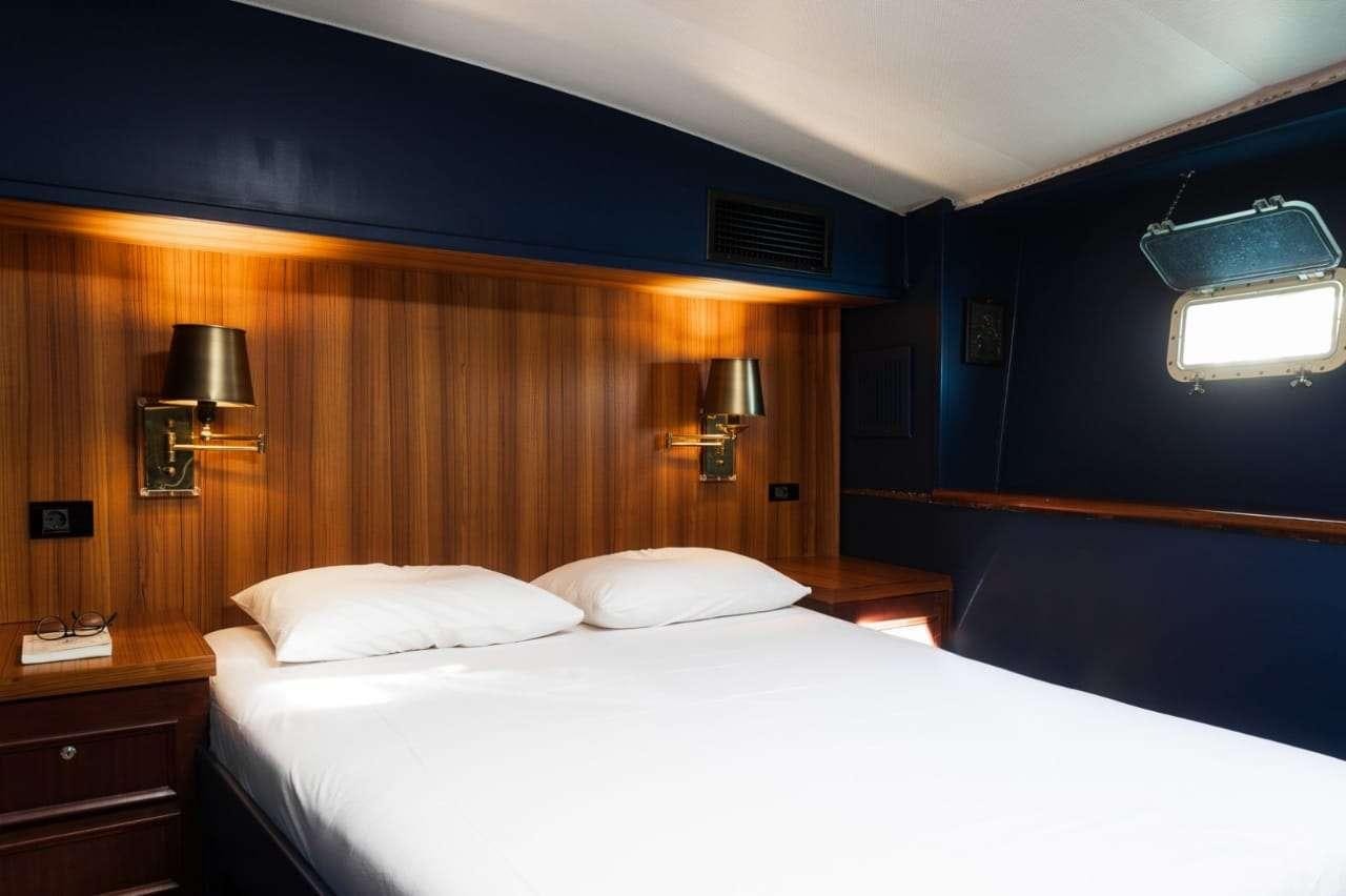 a bed with a white sheet aboard Theoxenia Yacht for Charter