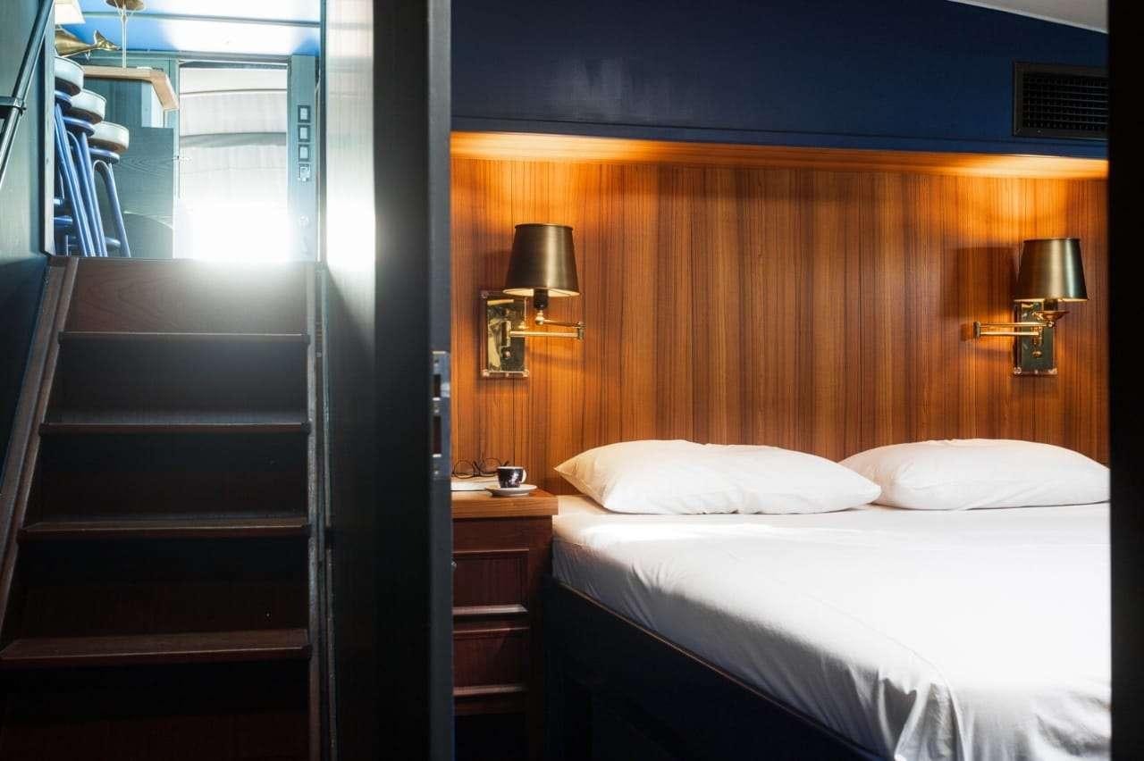 a room with a bed and a lamp aboard Theoxenia Yacht for Charter