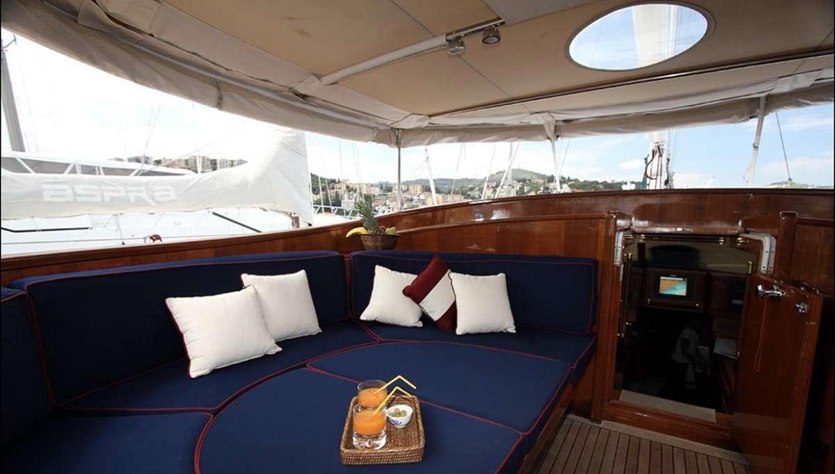 a blue couch with pillows and a table with a glass window aboard MALIZIA Yacht for Charter