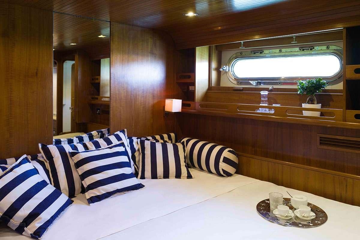 a room with a large white table and a white table with white and blue pillows aboard MALIZIA Yacht for Charter