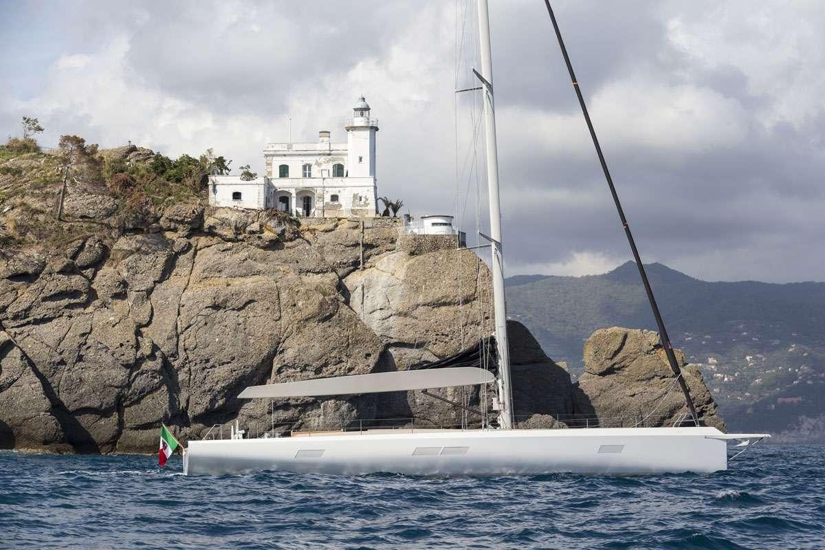 a boat on a body of water with a lighthouse in the background aboard KARMA Yacht for Charter