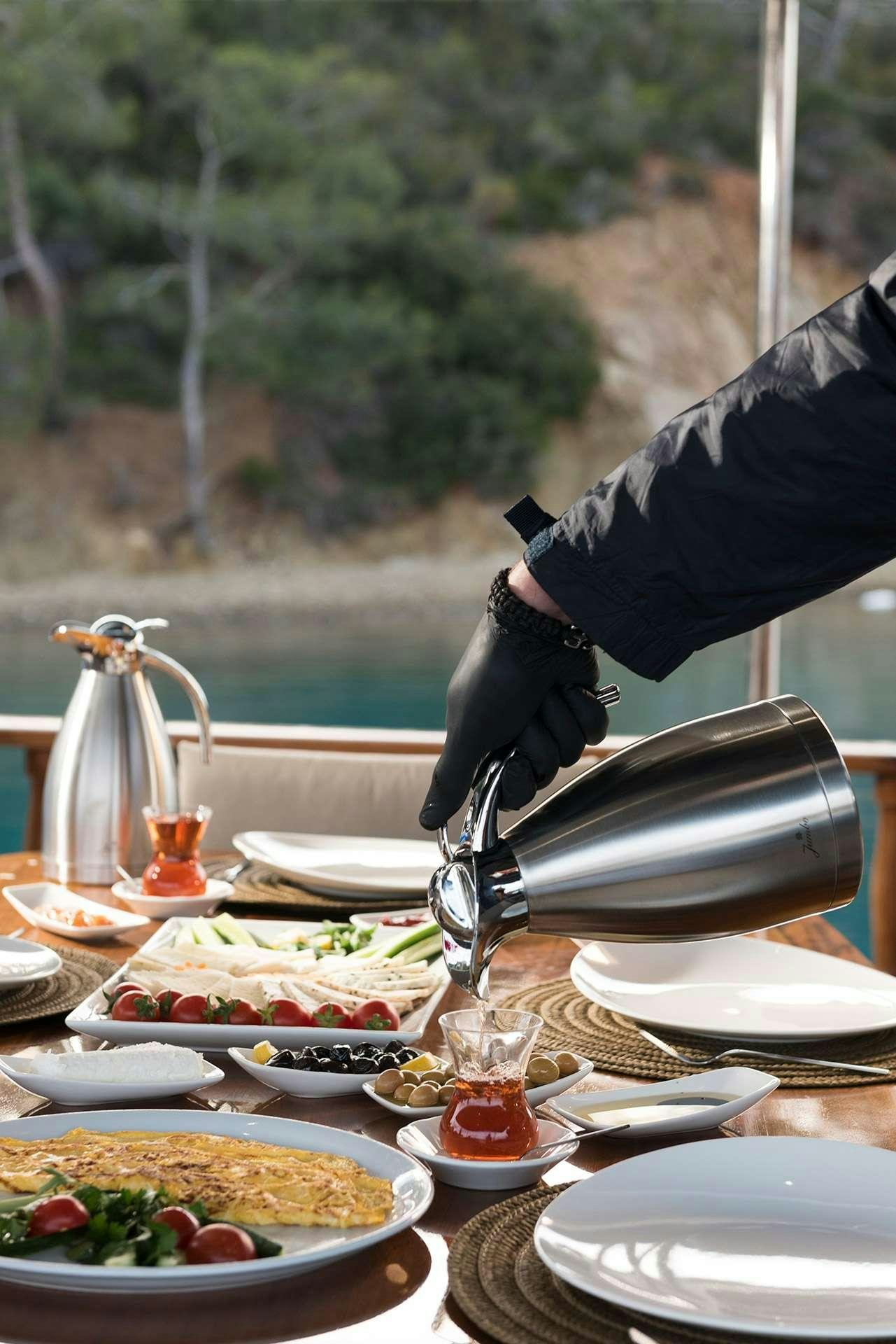 a person pouring liquid into a glass aboard SERENAD A Yacht for Charter