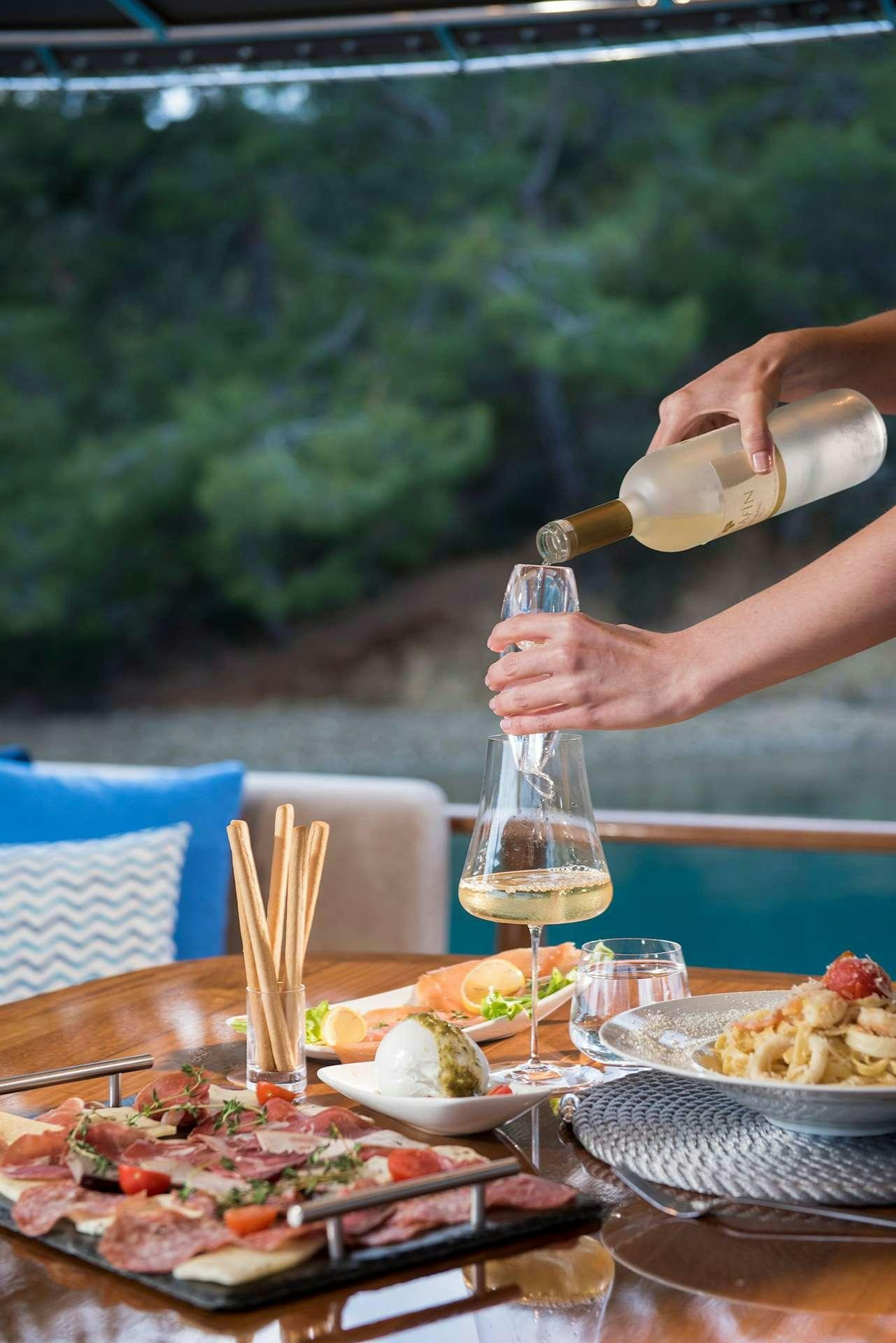 a person pouring a glass of wine aboard SERENAD A Yacht for Charter