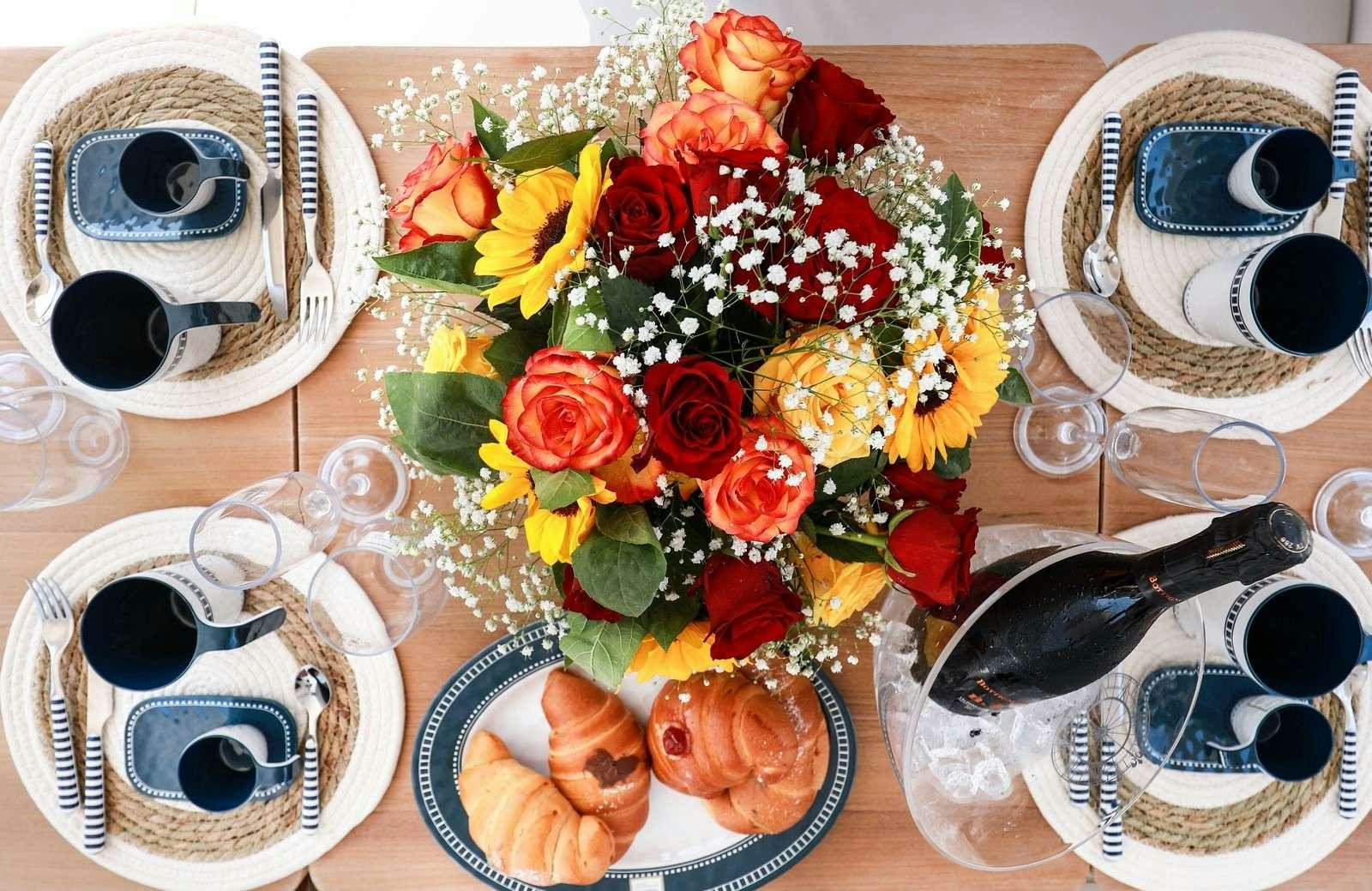 a table with a bouquet of flowers and a mug on it aboard EVA II Yacht for Charter