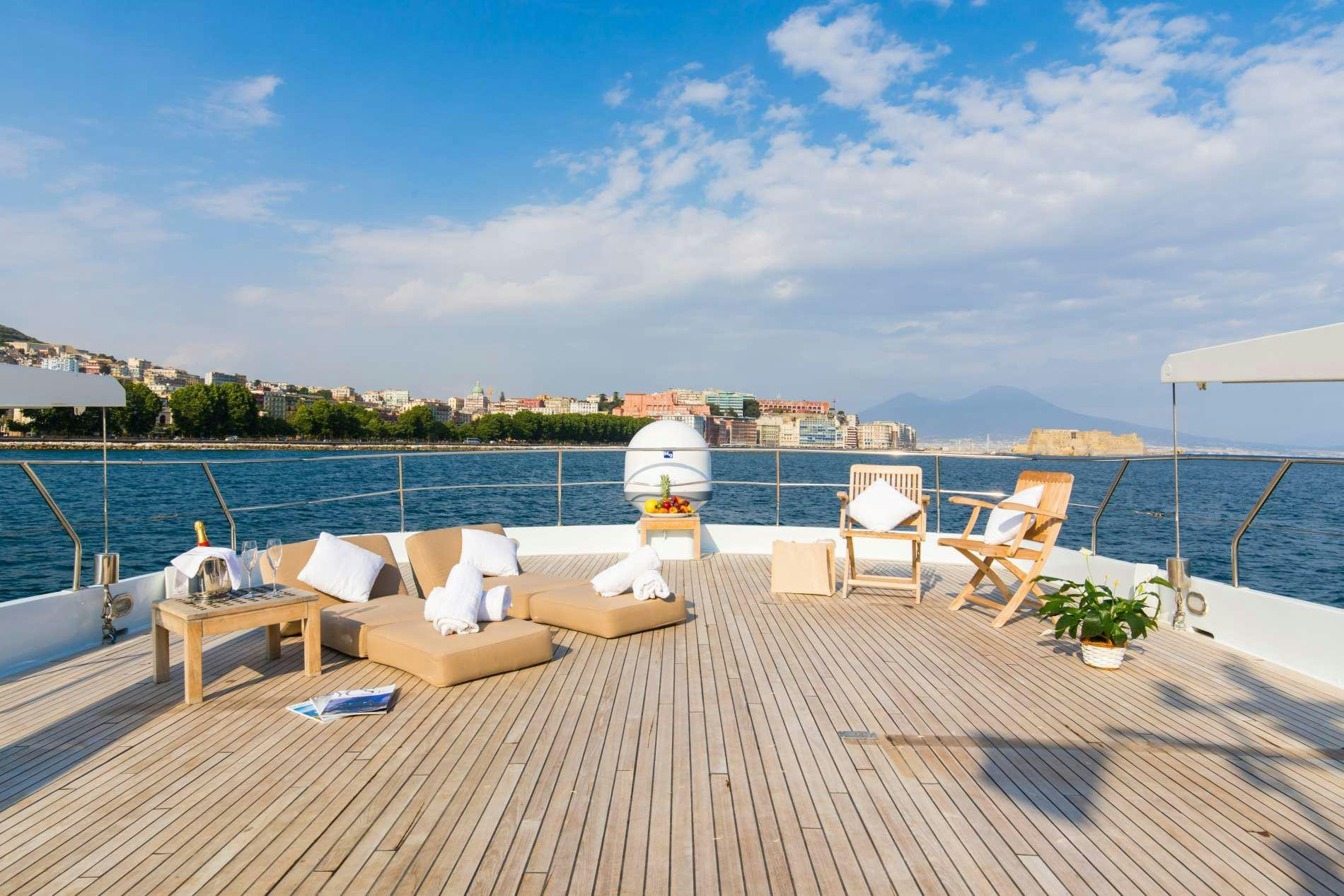 a deck with chairs and tables on it by a body of water aboard GITANES Yacht for Charter
