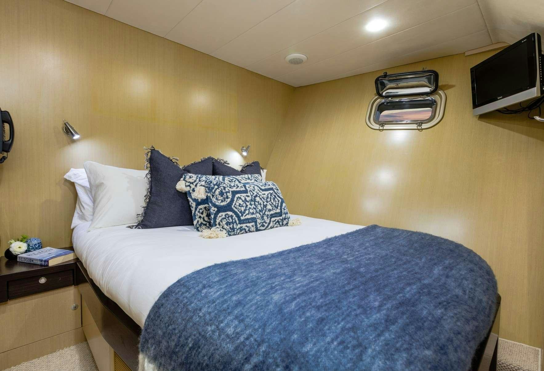 a bed with blue sheets aboard TEXAS T Yacht for Charter