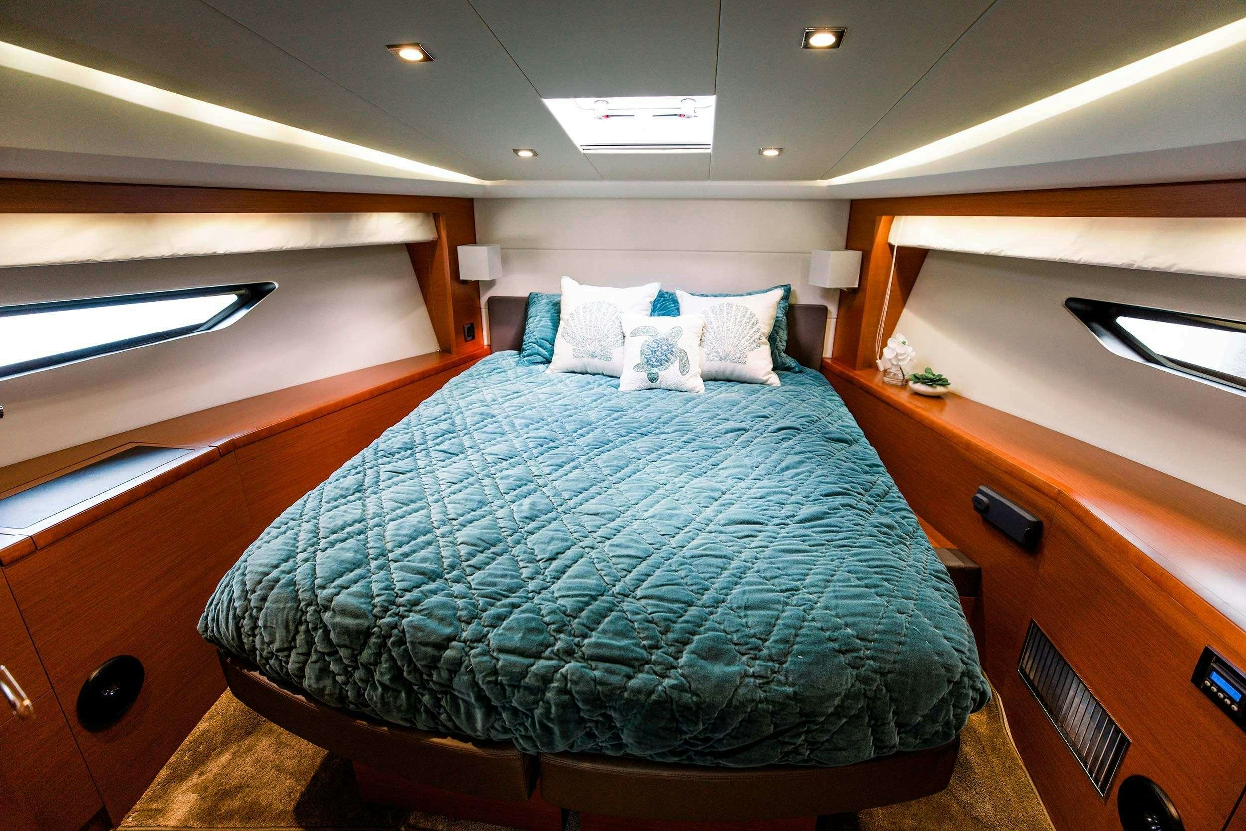 a bed with a blue and white comforter and a wooden dresser aboard Patinga, Fort Lauderdale Yacht for Charter