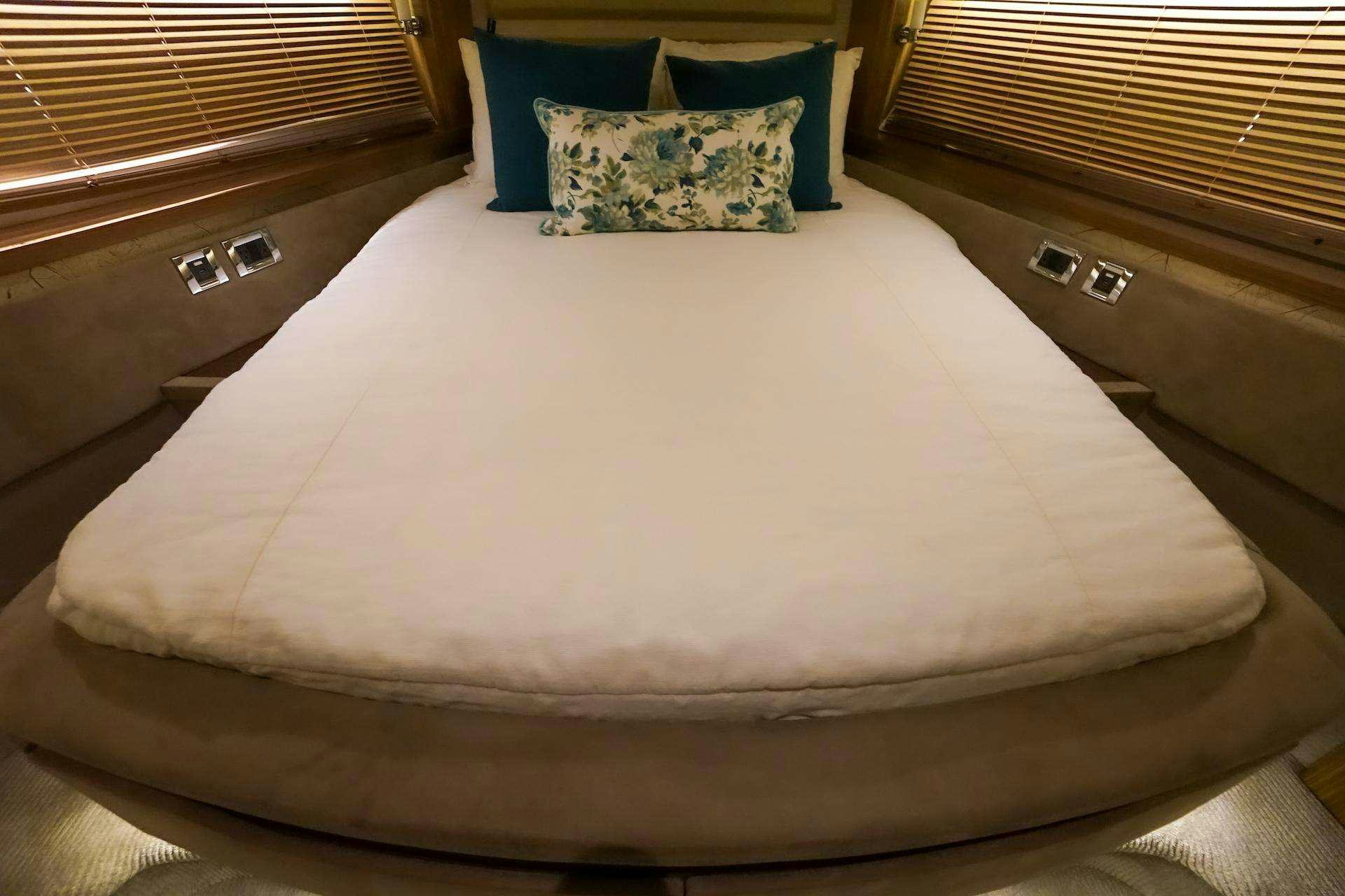 a bed with a white sheet and blue pillow aboard ISLANDER Yacht for Charter