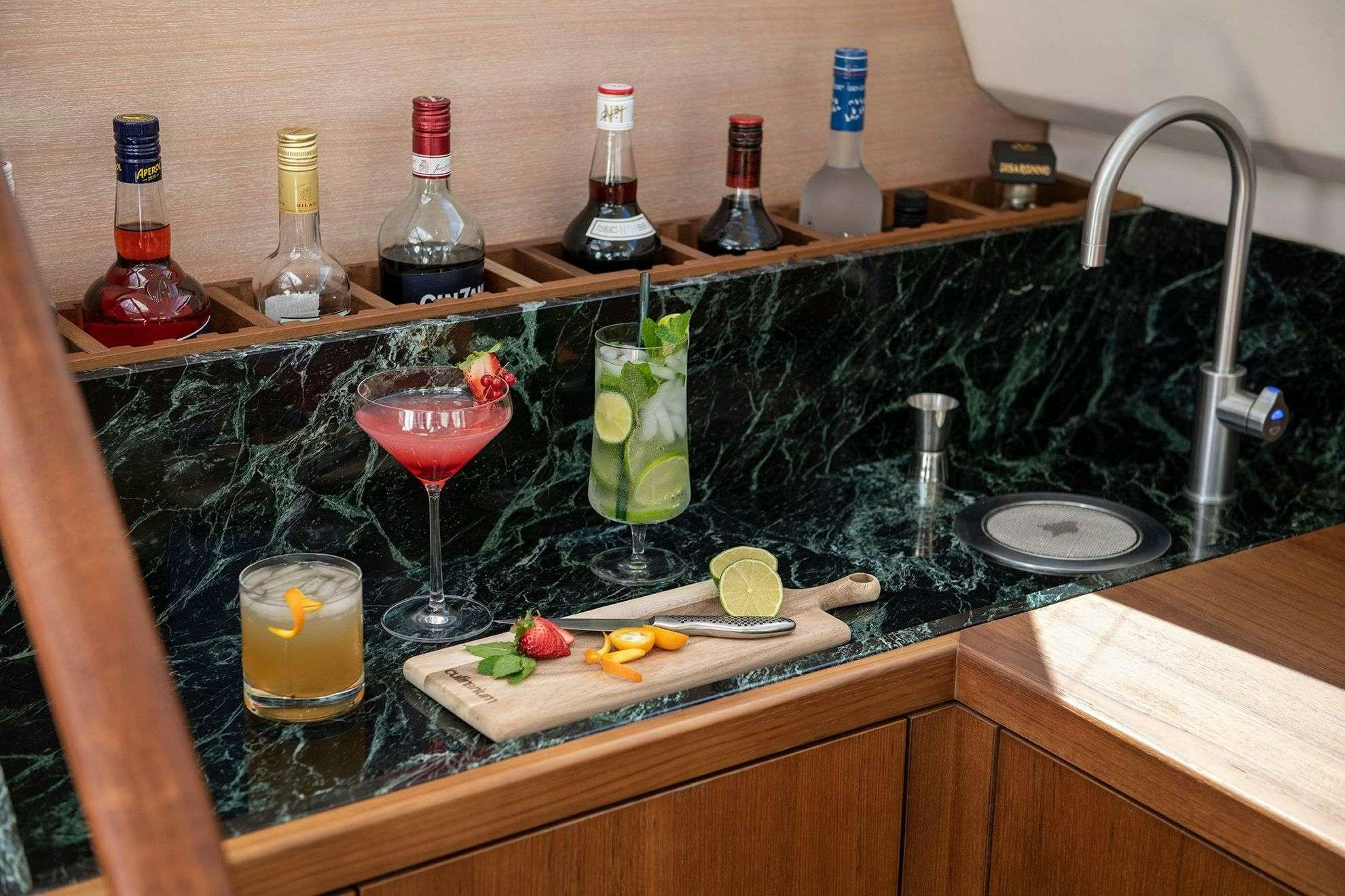 a hand holding a glass of wine next to a sink full of food aboard KARIBU Yacht for Charter