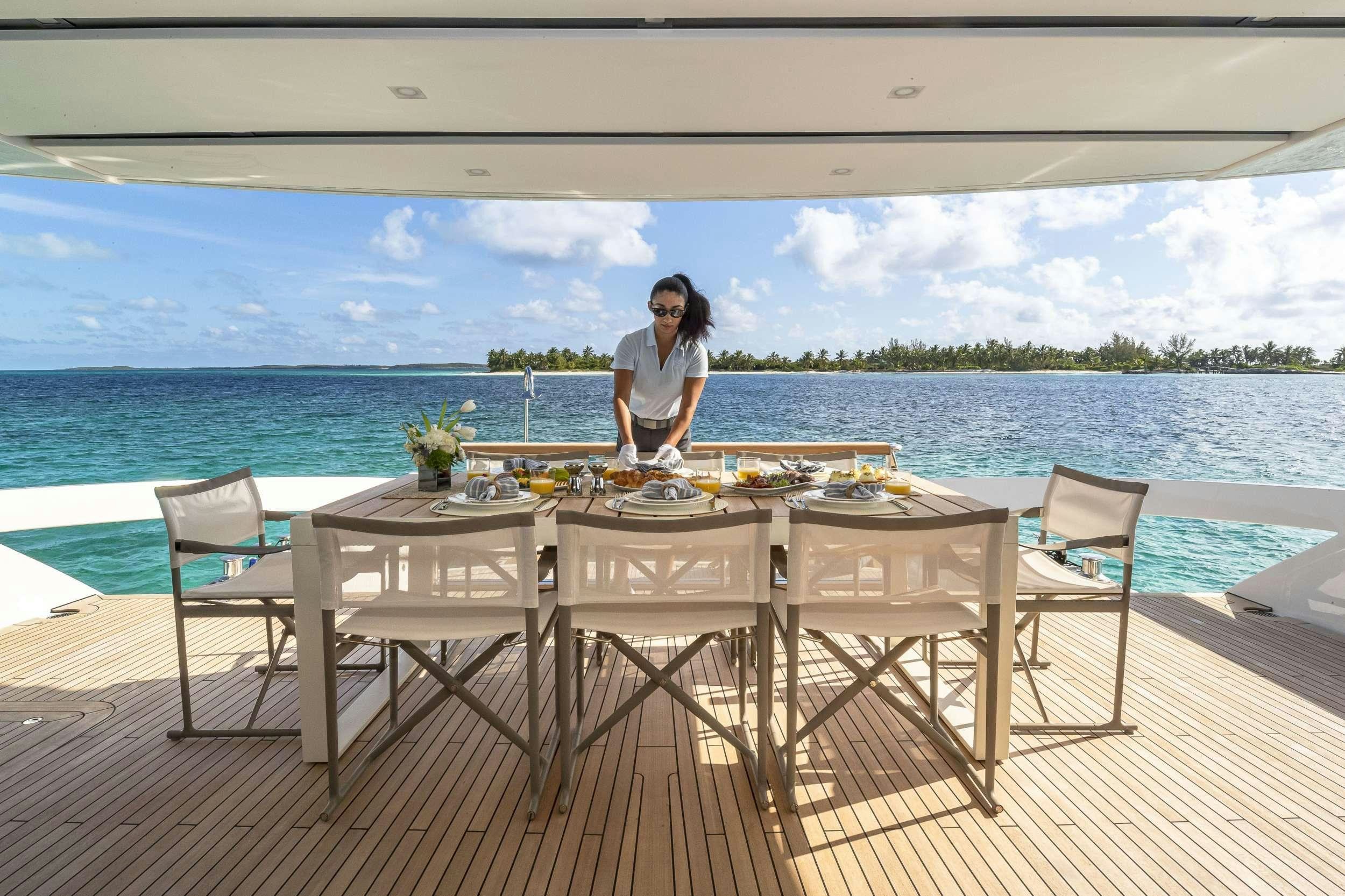 a person sitting at a table on a deck overlooking a body of water aboard NO MATTER WHAT Yacht for Charter