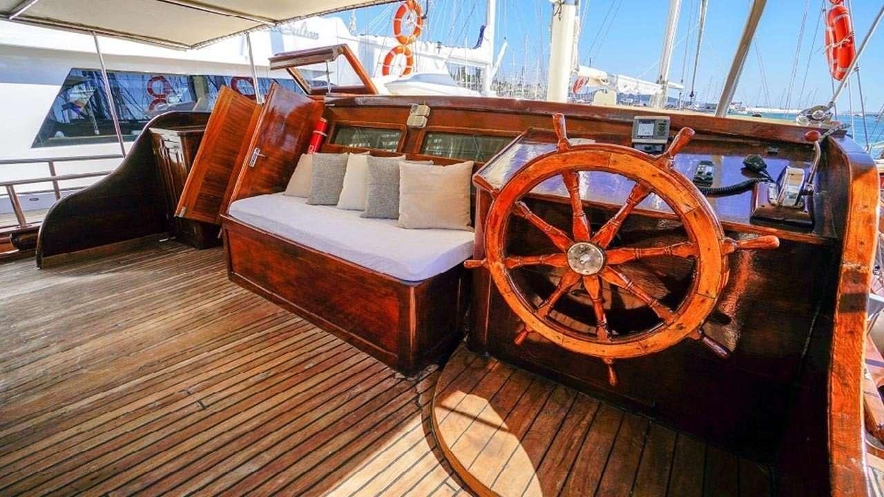 a wooden boat with a large orange wheel aboard AMETIST A Yacht for Charter