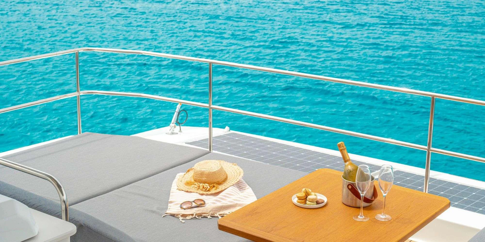 a table with a sandwich and drinks on it by the water aboard SEMPER FIDELIS Yacht for Charter