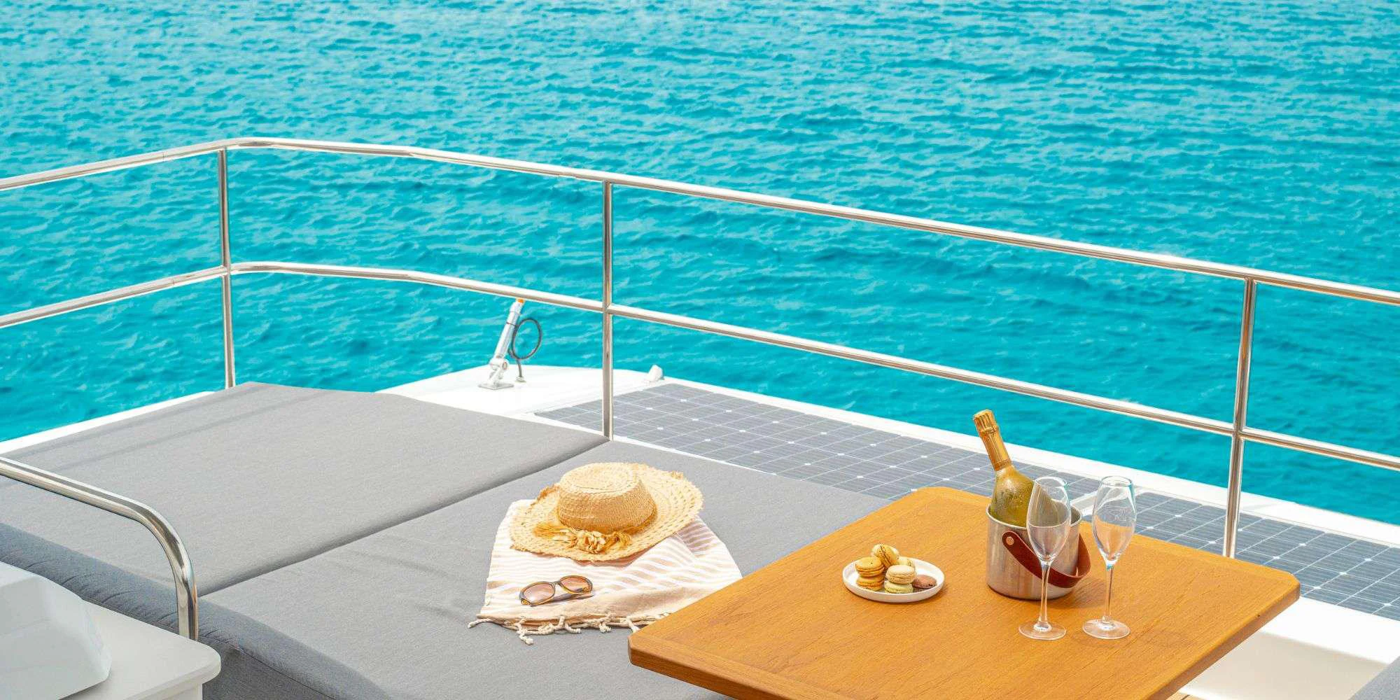 a table with a sandwich and drinks on it by the water aboard SEMPER FIDELIS Yacht for Charter