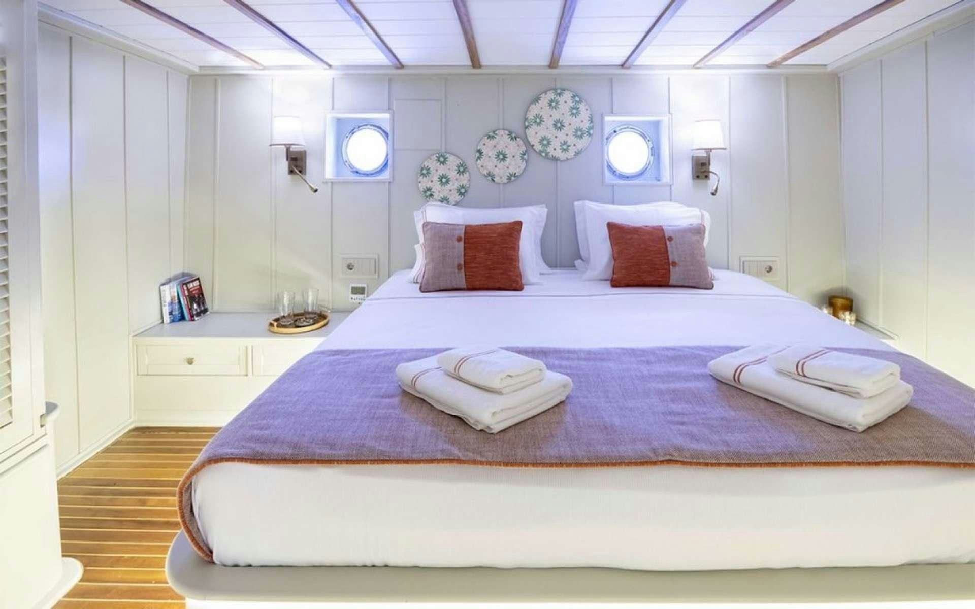 a large bed with a purple comforter and pillows aboard CAUSTIC Yacht for Charter