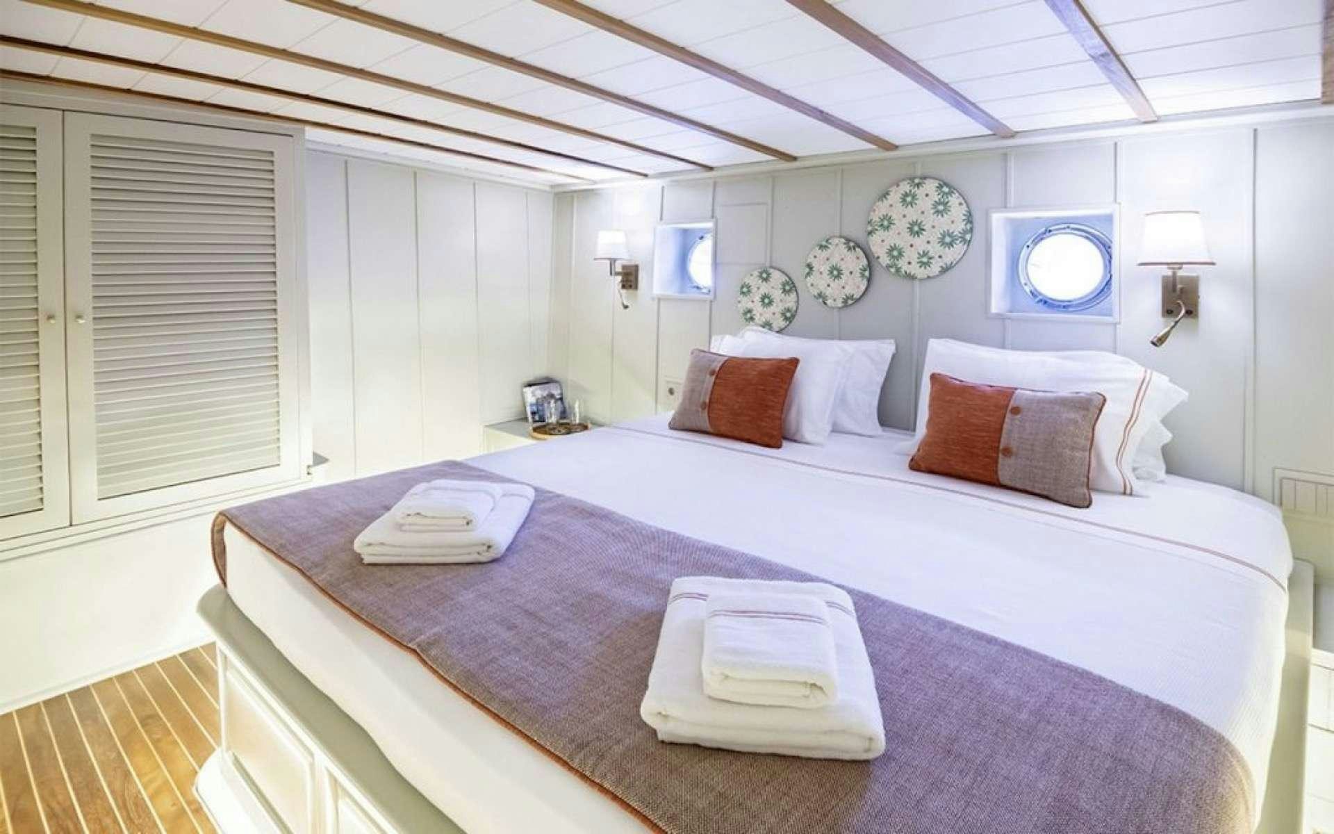 a bed with a white bed spread aboard CAUSTIC Yacht for Charter