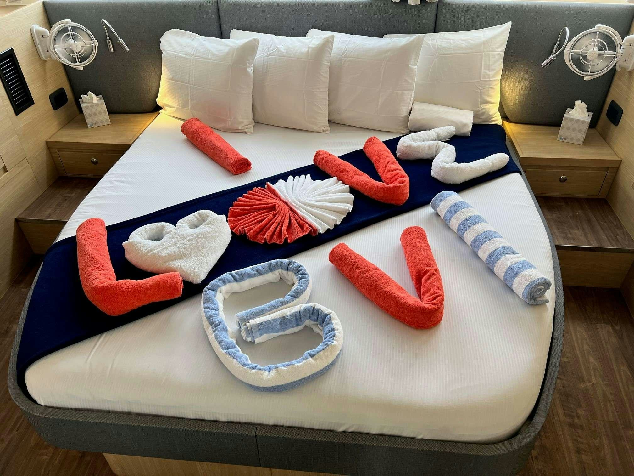 a bed with a blue sheet and red pillows aboard GO TEAM Yacht for Charter
