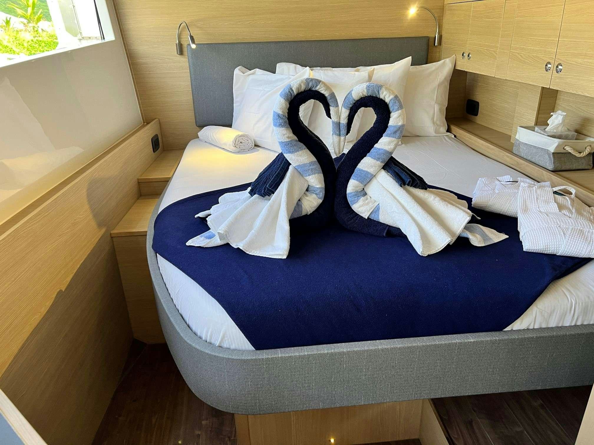 a bed with white sheets and pillows aboard GO TEAM Yacht for Charter