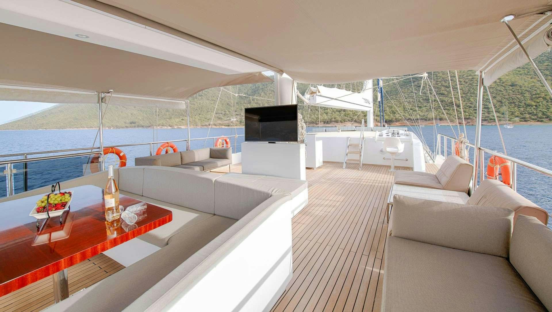 a room with a large screen and a table with chairs and a television aboard THE WALL Yacht for Charter