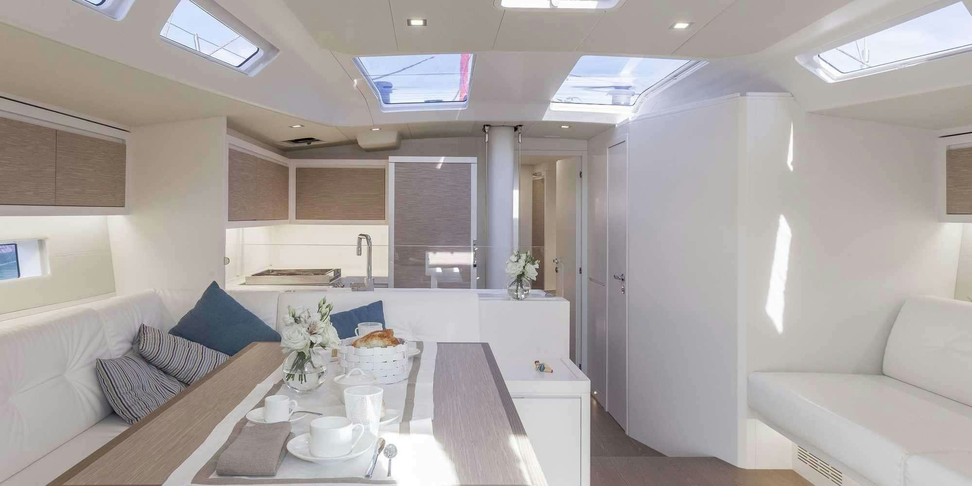 a white kitchen with a large white table and a white couch aboard PURA FOLLIA Yacht for Charter