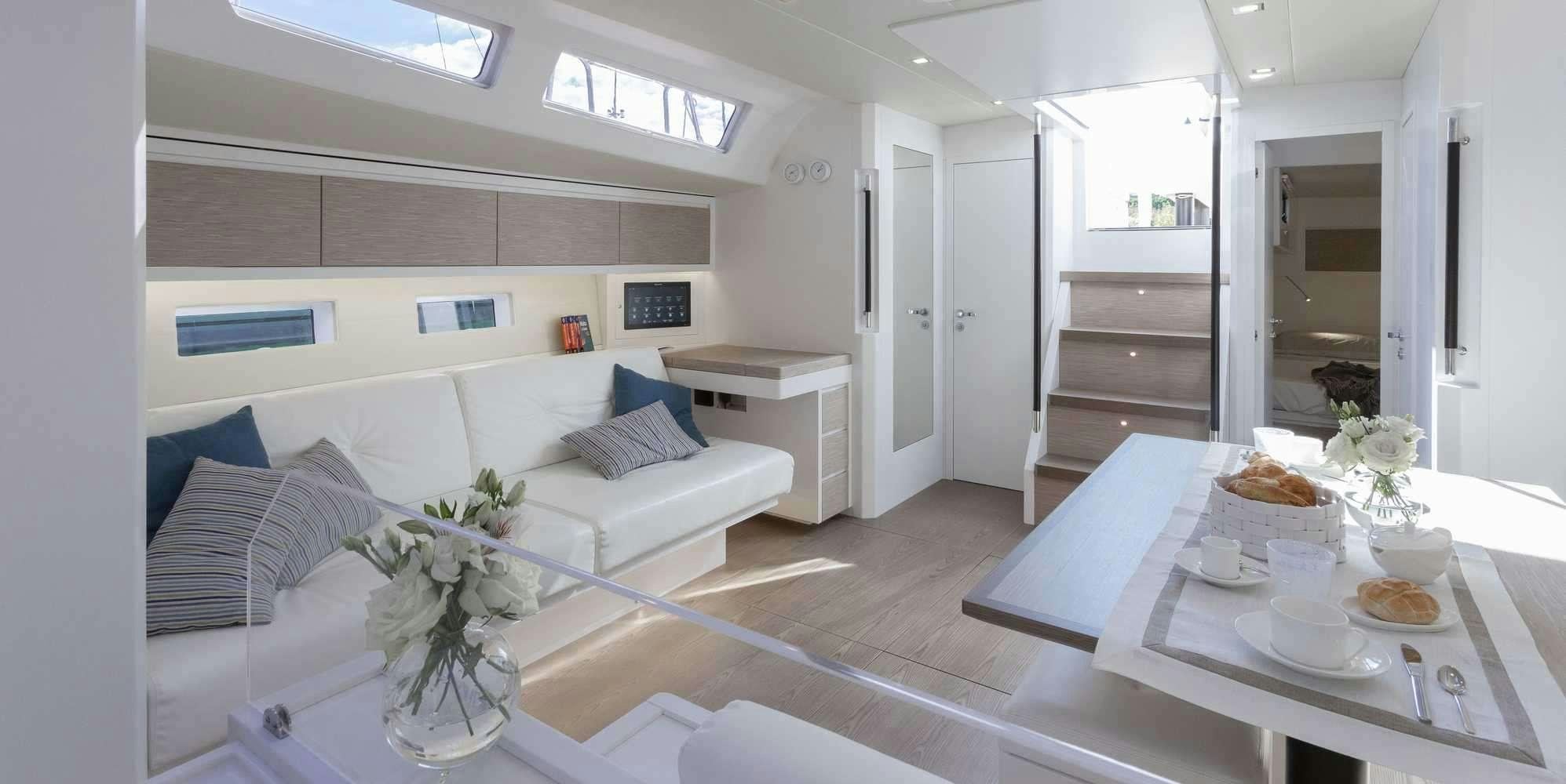 a large white living room with a white table and white couches aboard PURA FOLLIA Yacht for Charter