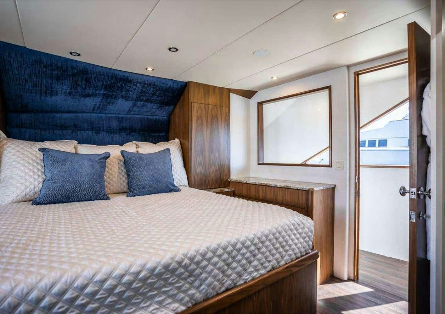 a bed with a blue and white comforter and pillows aboard A PLACE IN THE SUN Yacht for Charter