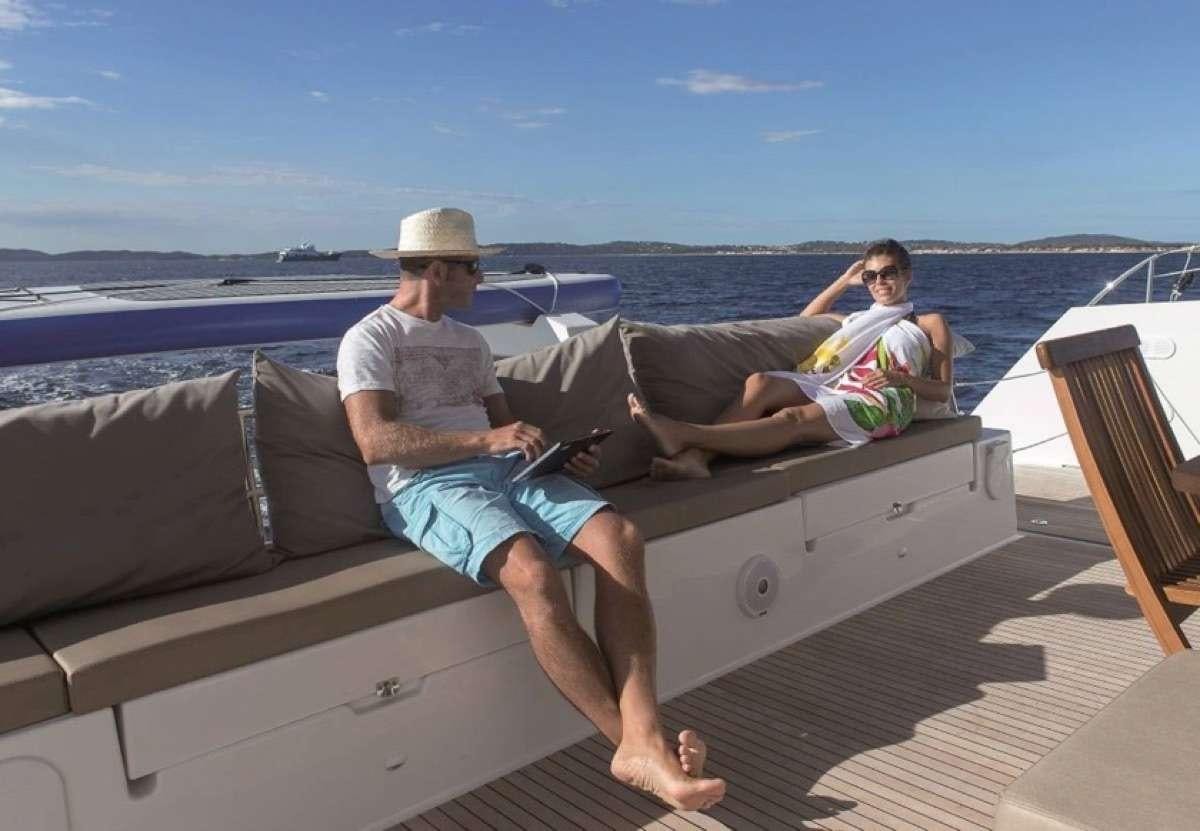 a man and woman sitting on a couch on a dock aboard Daydreams Yacht for Charter