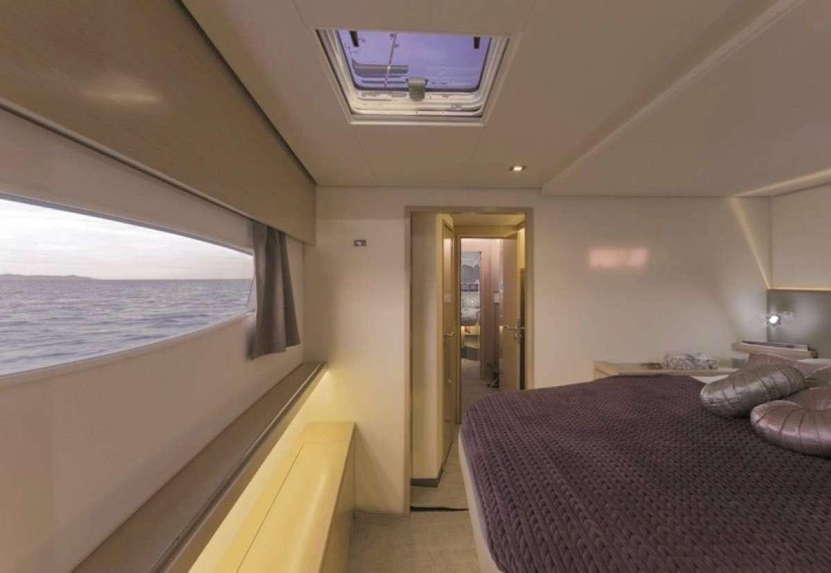 a bedroom with a bed and a window aboard Daydreams Yacht for Charter