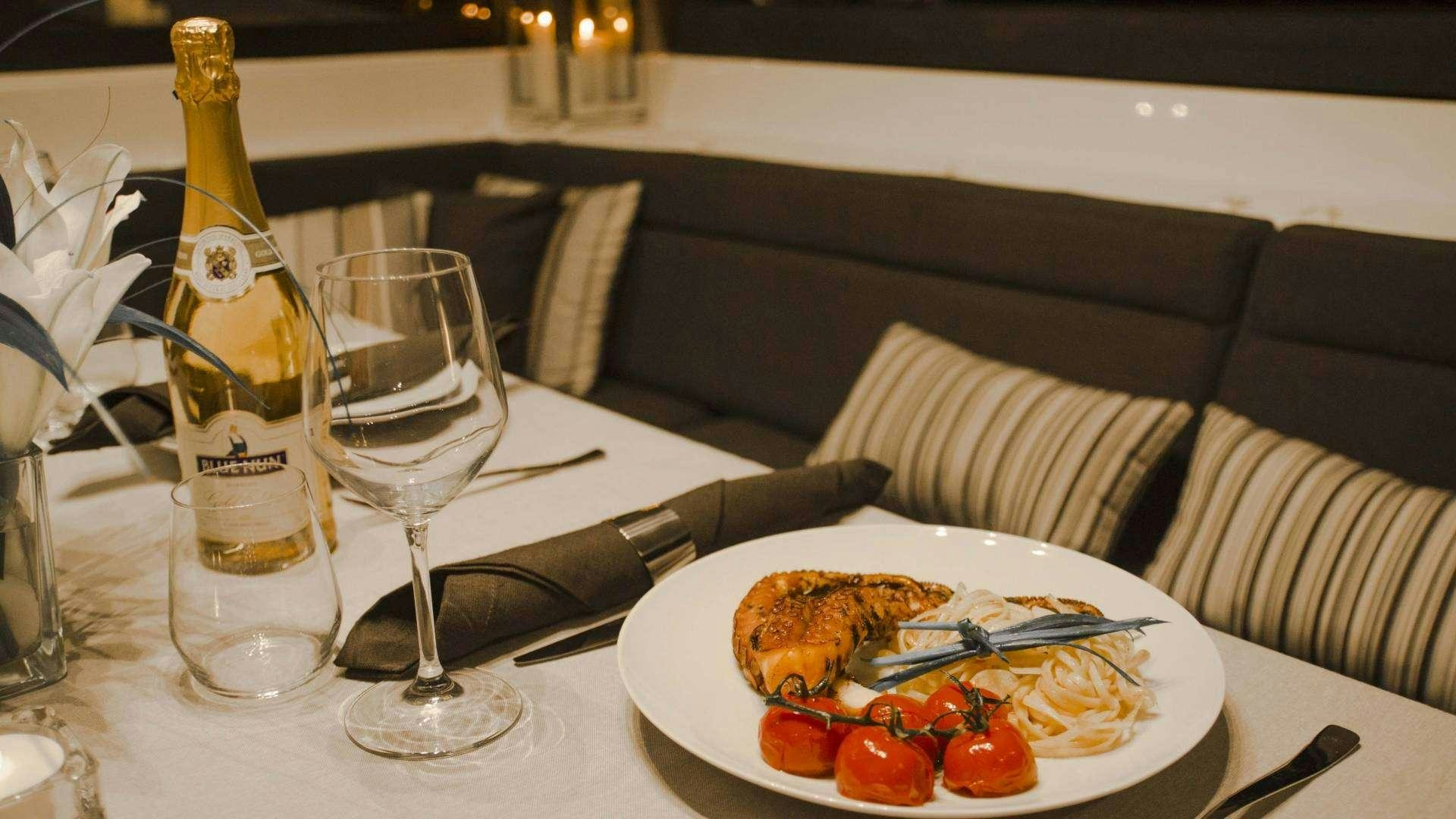 a bottle of wine and a plate of food on a table aboard Alyssa Yacht for Charter