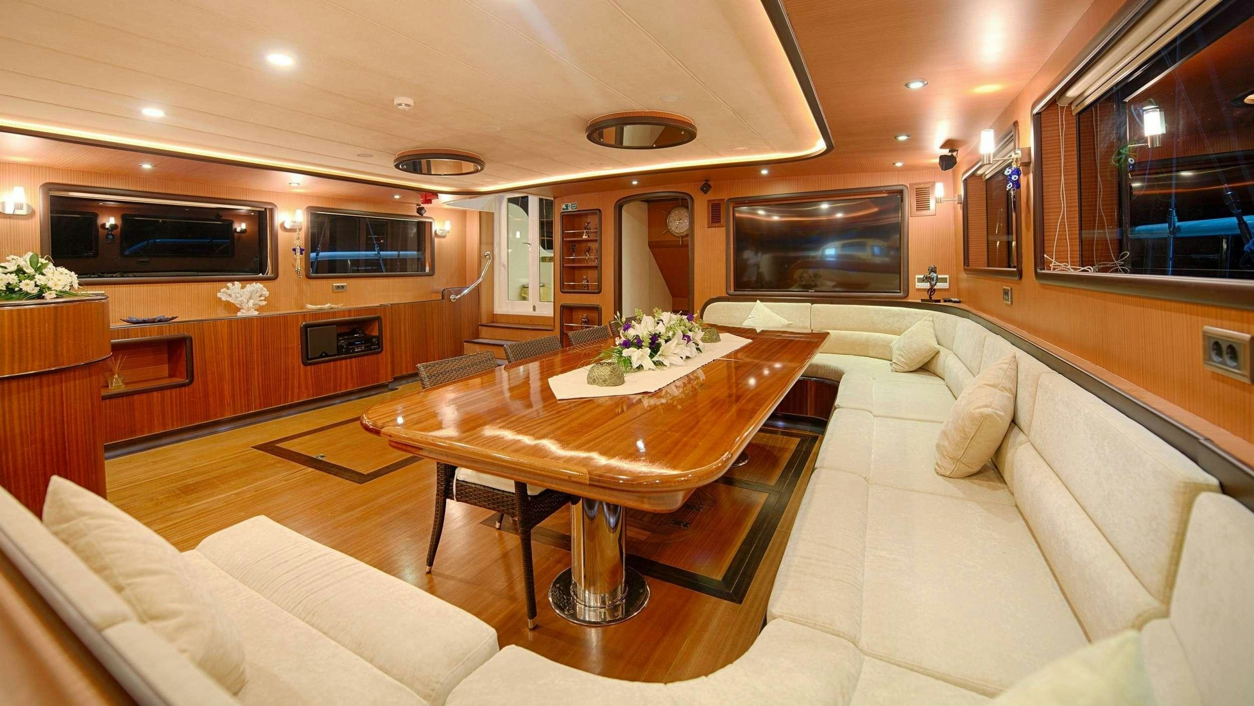a living room with a table and couches aboard QUEEN OF SALMAKIS Yacht for Charter