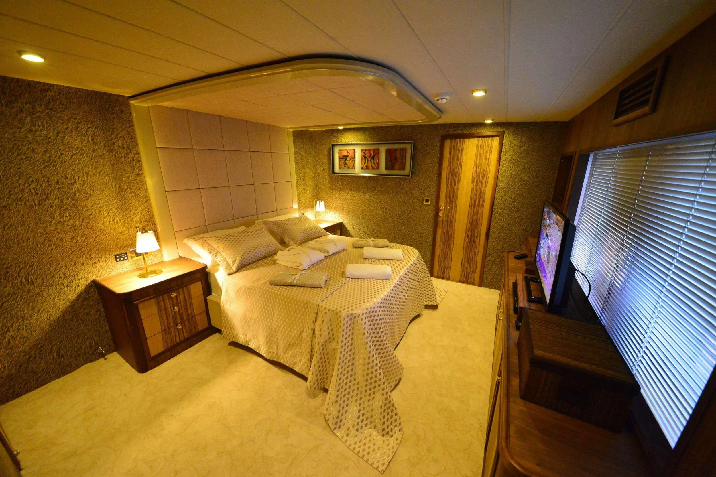 a bedroom with a bed and a desk aboard IMMERSIVE Yacht for Charter