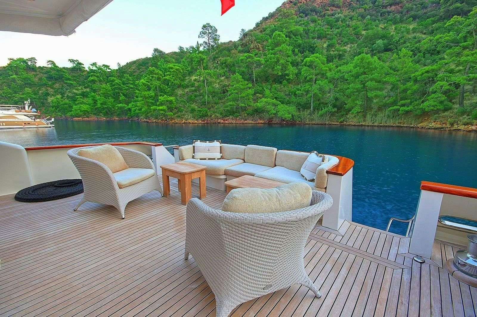 a deck with chairs and tables on it by a body of water aboard BLANCO Yacht for Charter