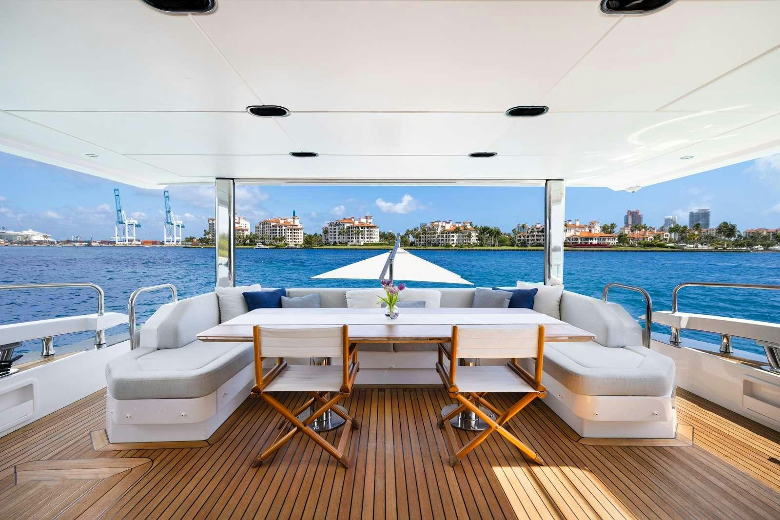 a room with a table and chairs on a deck overlooking a body of water aboard RINA Yacht for Charter