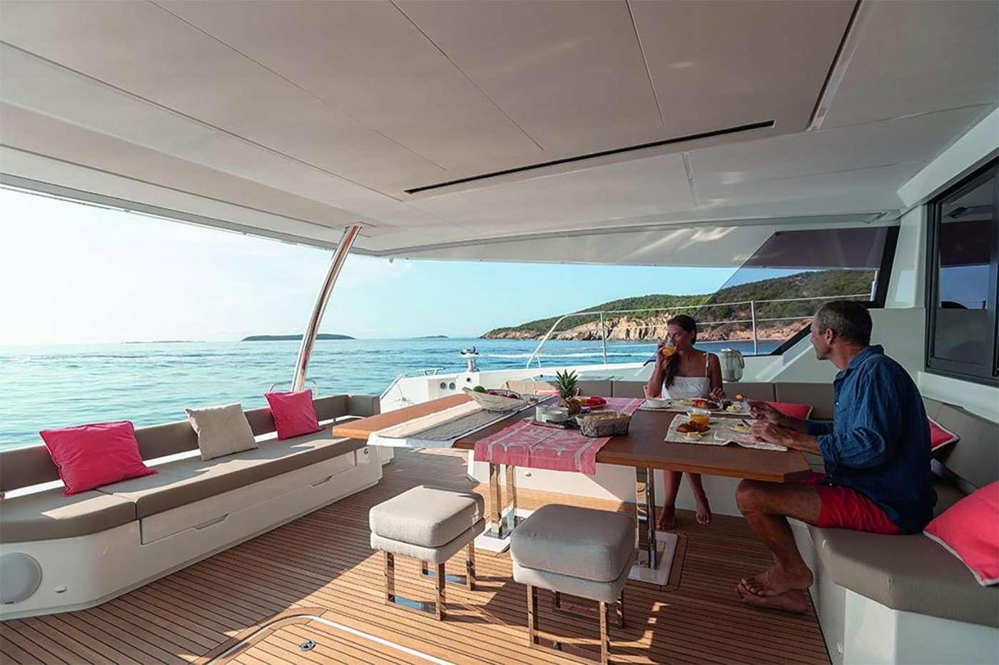 a couple of people sitting at a table outside on a boat aboard OCEANUS Yacht for Charter