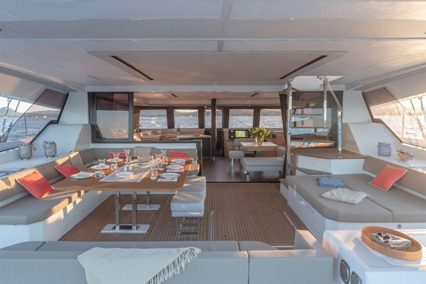 a room with a large window and a table with chairs and a shelf aboard OCEANUS Yacht for Charter