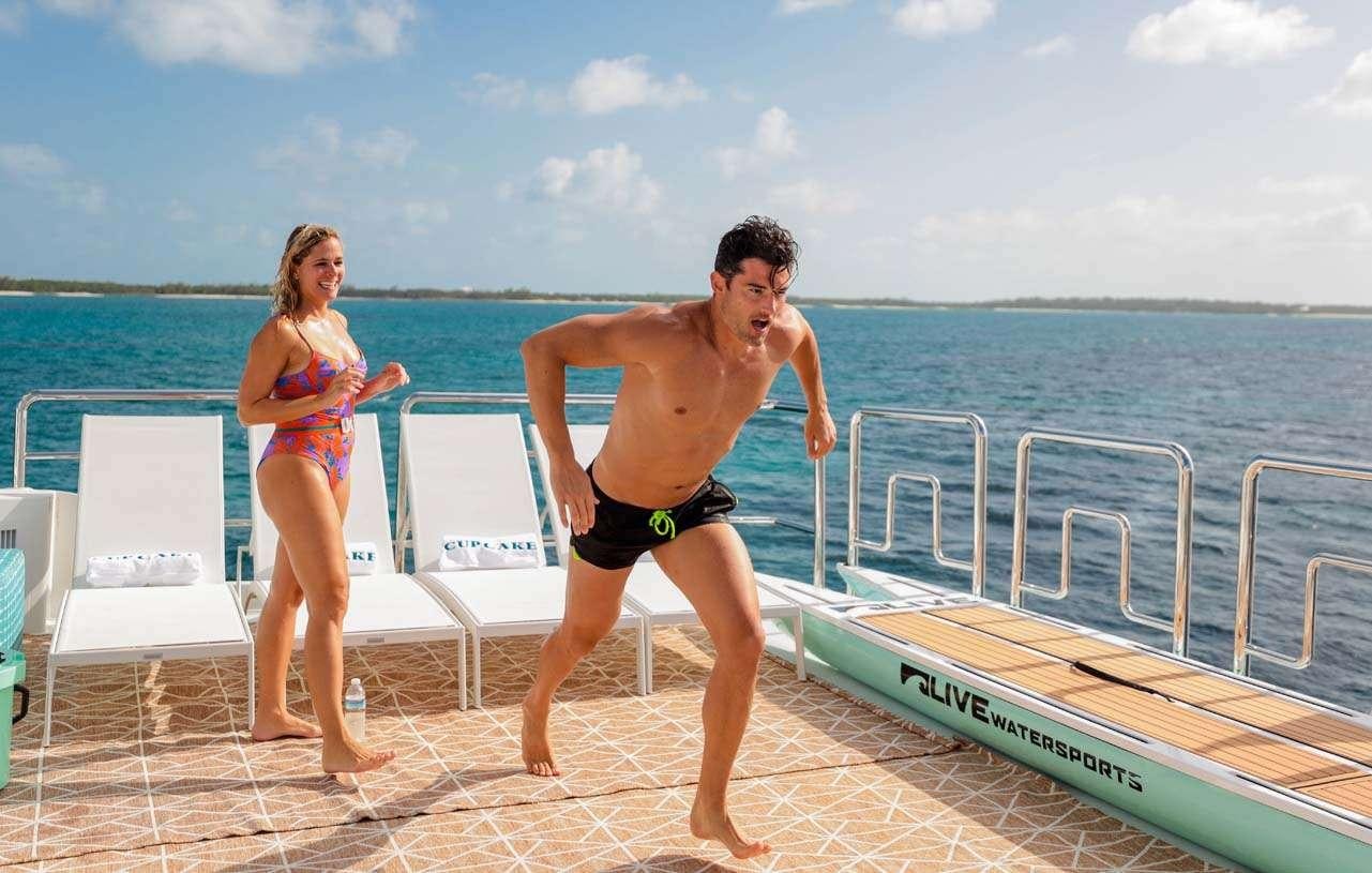 a man and woman running on a boardwalk by the water aboard CUPCAKE Yacht for Charter