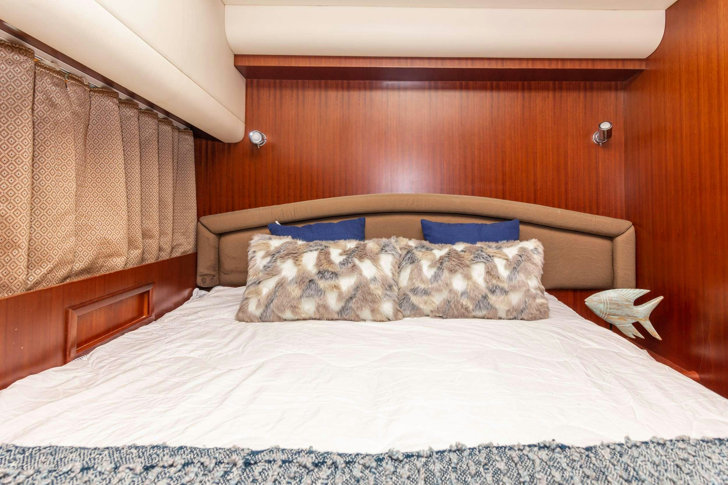 a bed with a white sheet and a blue pillow aboard VIAGGIO Yacht for Charter