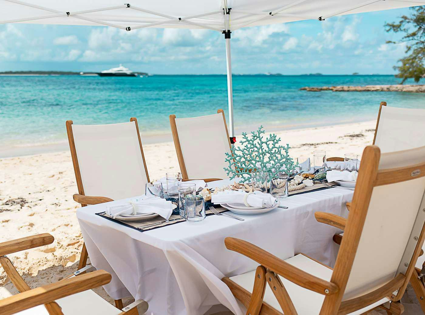 a table set for a dinner on a beach aboard ACACIA Yacht for Charter