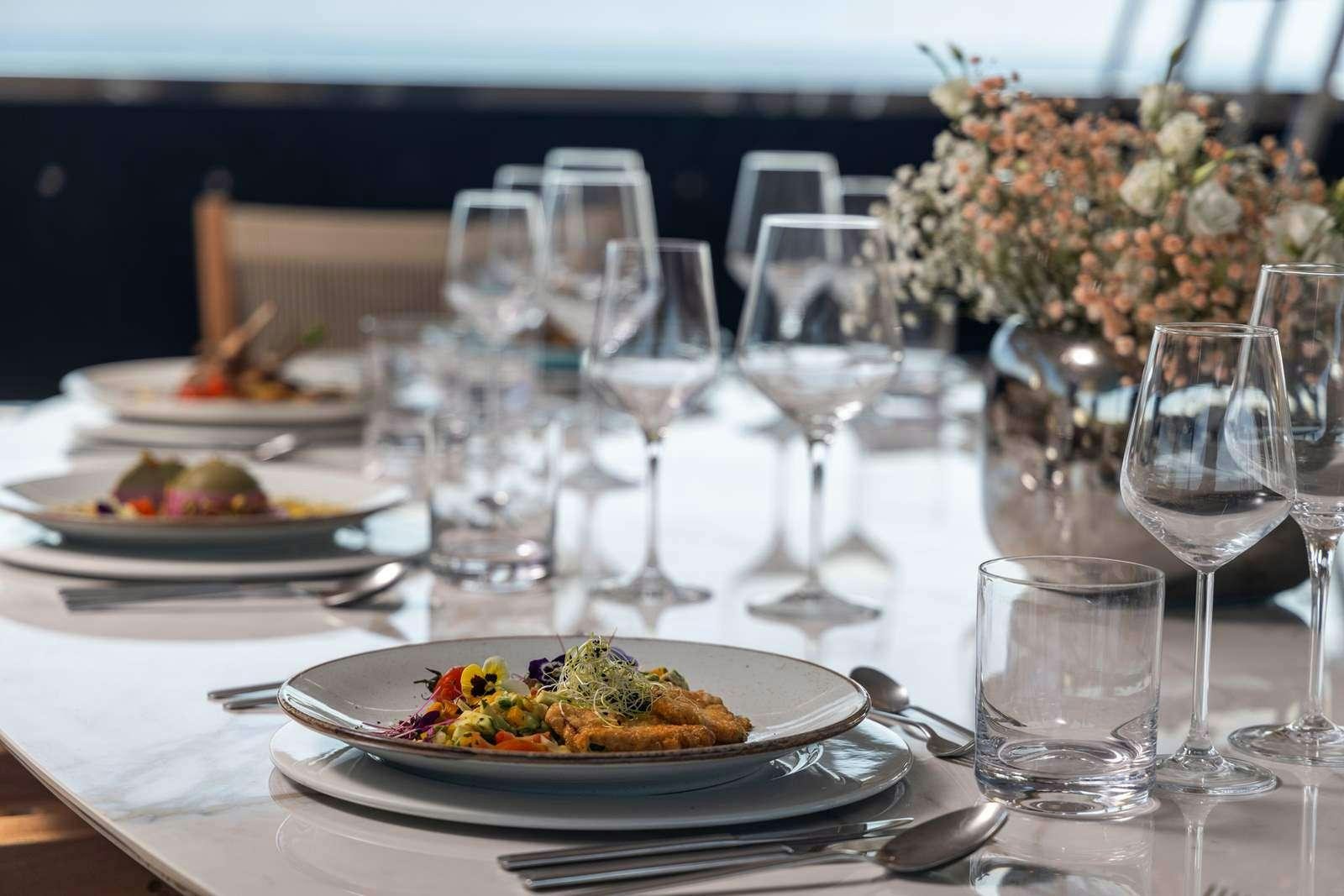a table with plates and glasses of food on it aboard OLIMP Yacht for Charter