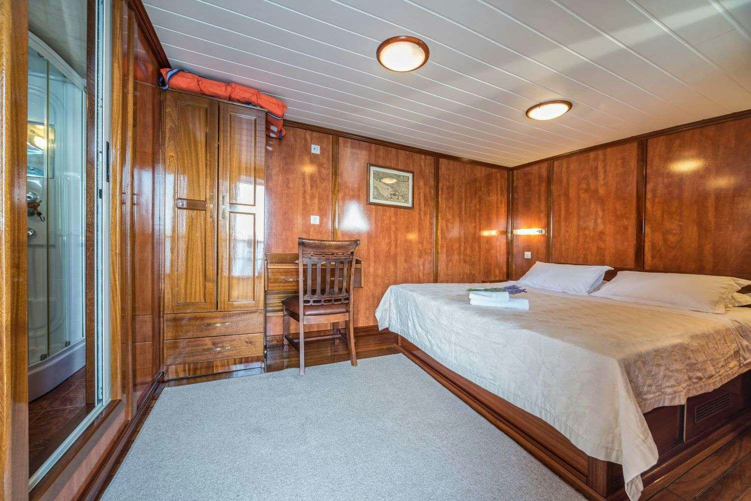 a bedroom with a bed and a chair aboard LUNA Yacht for Charter