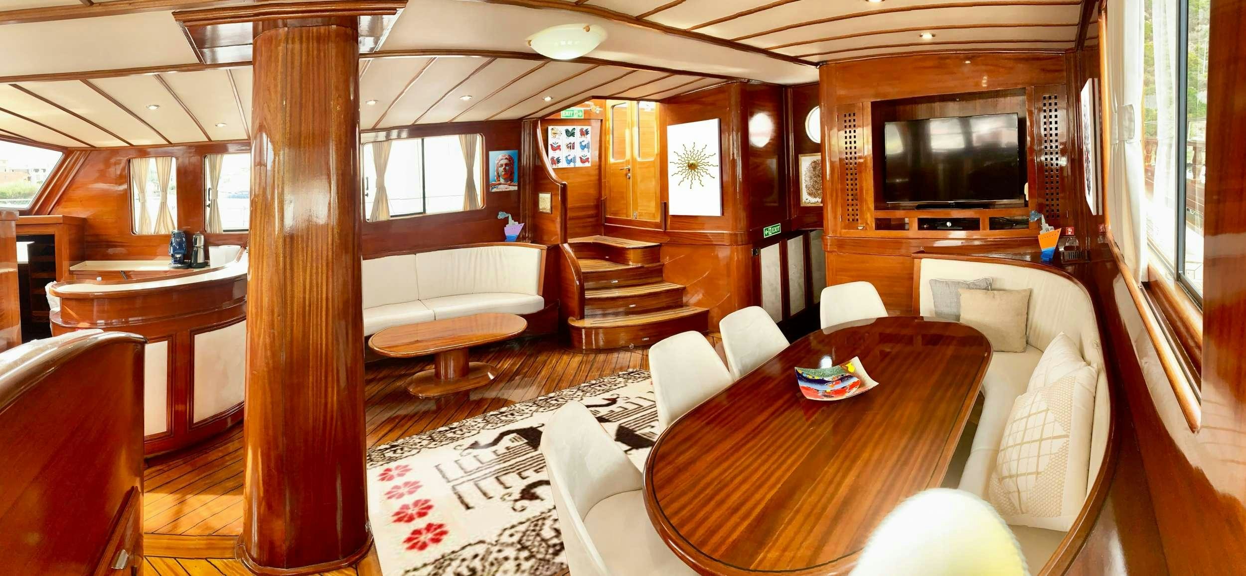 a living room with a wood table and couches aboard ELIANORA Yacht for Charter